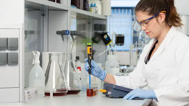Seorang analis sedang mengukur instrumen pH meter di laboratorium